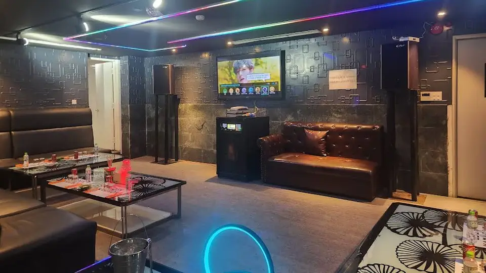 다낭 에덴 가라오케 에덴 가라오케의 블랙 텍스처 벽면과 RGB 네온 천장 조명, 가죽 소파 및 대형 TV가 갖춰진 프라이빗 룸 내부