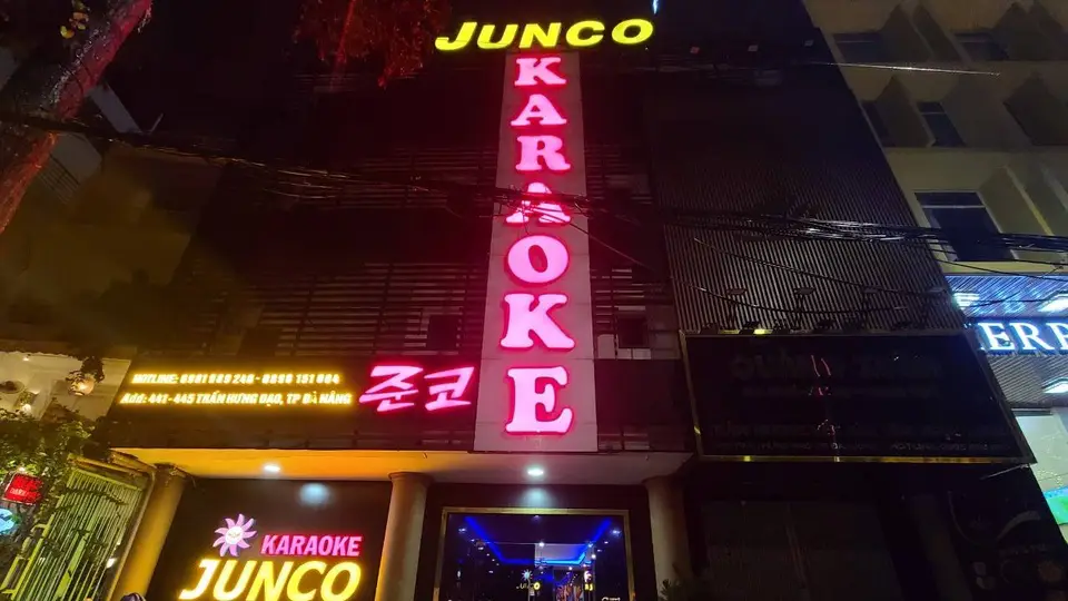 다낭 준코 가라오케 준코 가라오케의 노란색 영문 간판과 핑크 한글 네온사인이 돋보이는 다층 건물 야간 외관