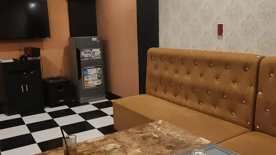 다낭 원오페라 가라오케 캐러멜 색상 버튼 소파와 소형 냉장고, TV가 구비된 아늑한 소형 가라오케 룸 내부