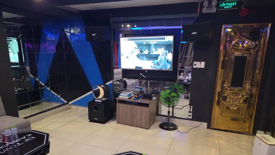 다낭 업타운 가라오케 블랙 미러 패널과 대형 LED TV, 골드 프레임 장식 도어가 설치된 업타운 가라오케 개인 룸 내부