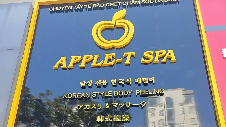 다낭 애플 스파 애플 스파의 골드 컬러 로고와 한국어·영어·일본어·중국어가 새겨진 네이비 블루 외관 간판
