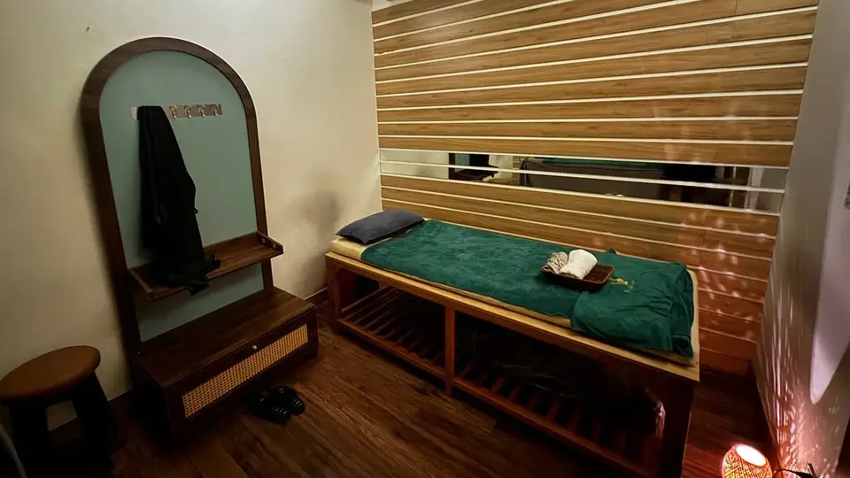 다낭 청룡열차 청룡열차 룸 내부의 그린 커버 원목 마사지 베드와 아치형 거울, 우드 슬랫 벽면 인테리어
