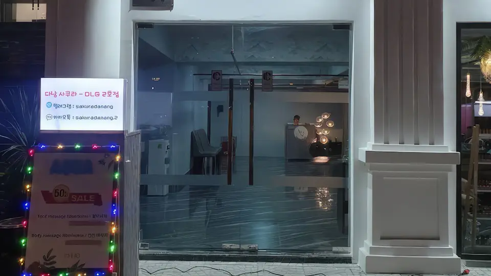 다낭 DLG 사쿠라 2호점 다낭 DLG 사쿠라 2호점 마사지 샵의 유리 외관과 네온 간판, 50% 세일 배너가 설치된 전경