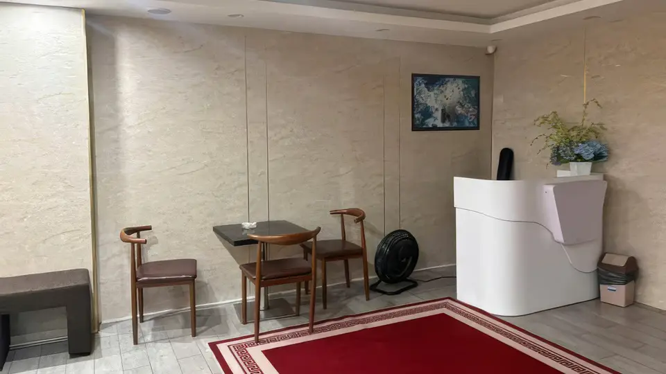 다낭 DLG 사쿠라 2호점 아이보리 대리석 벽면, 레드 카펫, 목재 의자와 화이트 프런트 데스크가 배치된 고급 리셉션 공간