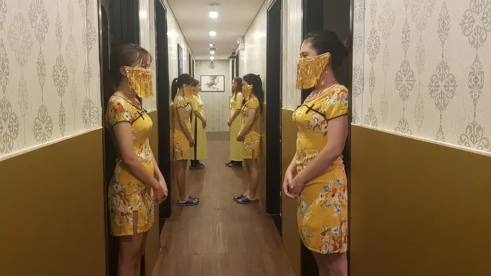 다낭 풍투이 스파 풍투이 마사지의 전통 치파오 유니폼을 착용한 전문 여성 테라피스트 두 명이 복도에 나란히 서 있는 모습
