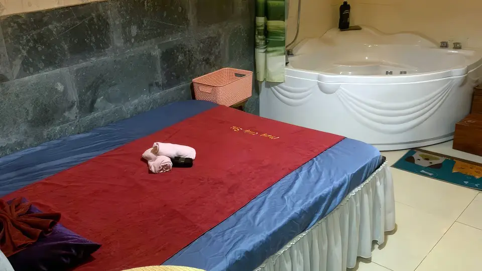 다낭 풍투이 스파 다크 스톤 벽면과 대형 코너 자쿠지 욕조, 붉은 마사지 베드가 함께 갖춰진 풍투이 마사지의 프라이빗 스파 룸