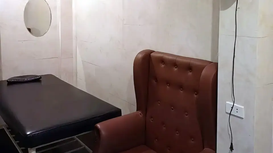하노이 어메이징 마사지 어메이징 마사지 룸 내부의 고급 갈색 윙체어와 블랙 마사지 베드, 원형 거울이 배치된 프라이빗 룸
