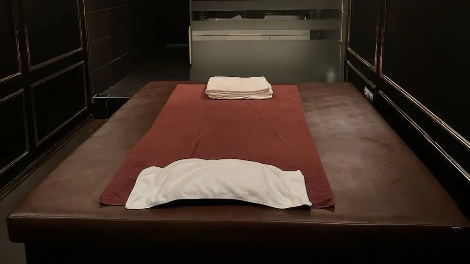 하노이 강남 스파 블랙 골드 패널 벽면과 정갈하게 세팅된 마사지 베드, 청결한 타월이 준비된 고급 마사지 룸 내부