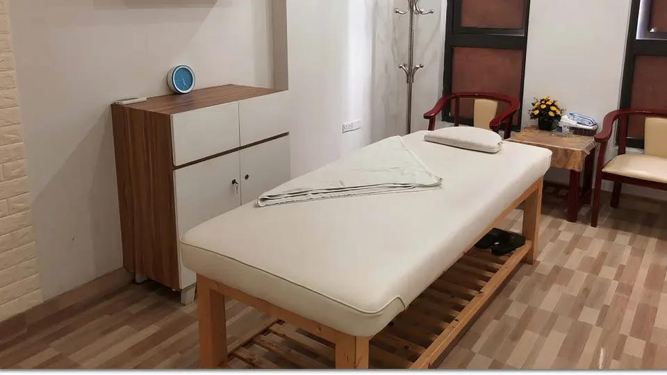 하노이 수 사우나 수 사우나의 원목 바닥과 밝은 조명 아래 정갈하게 세팅된 마사지 베드와 수납장