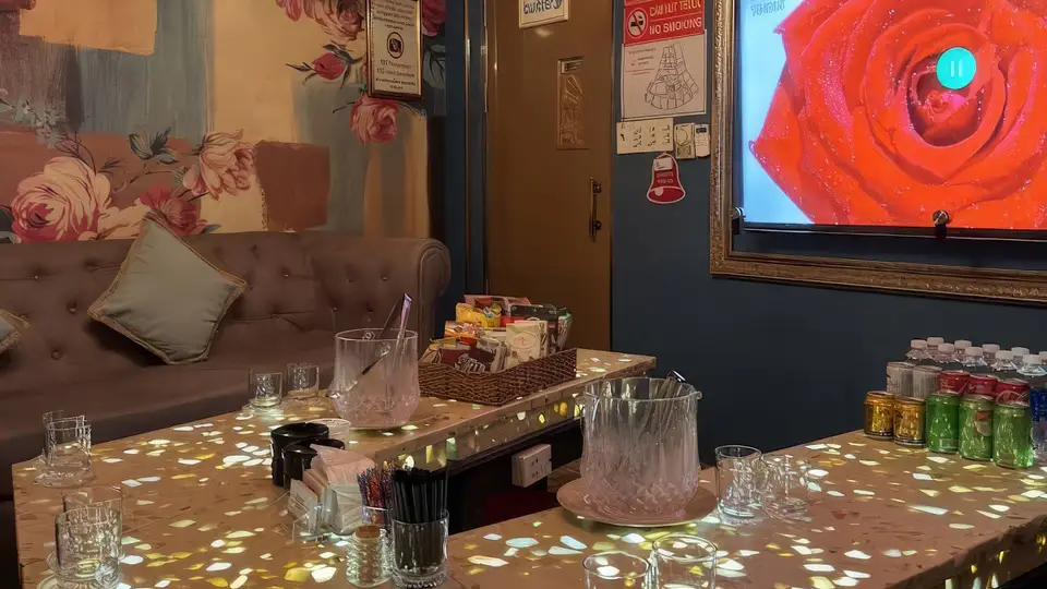 호치민 보스 가라오케 장미 패턴 벽지와 그레이 벨벳 소파, 골드 프레임 TV가 어우러진 가라오케 룸