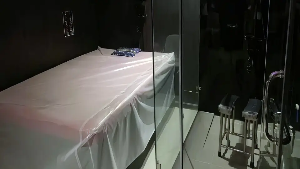 호치민 슈퍼맨 마사지 슈퍼맨 마사지 룸 내부 — 흰색 시트로 정갈하게 정돈된 마사지 베드, 유리 파티션 너머 샤워 공간과 발 받침대가 완비된 독립 룸