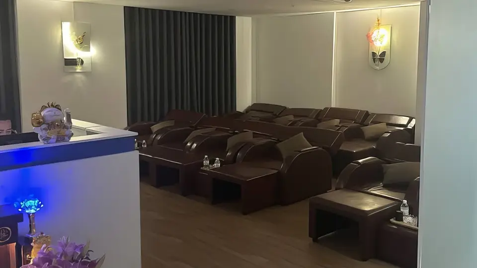 나트랑 클라우드 나인 클라우드 나인의 넓은 풋 마사지 라운지 내부, 다수의 갈색 리클라이너 마사지 베드와 블루 조명의 리셉션 카운터