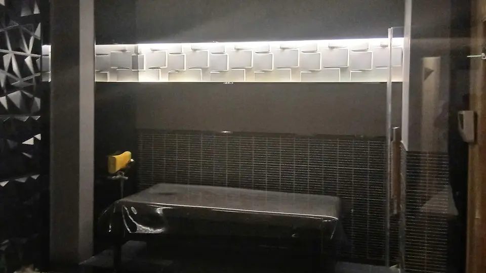 나트랑 나우 스파 화이트 큐브 패턴 조명 월과 유리 파티션, 블랙 마사지 베드가 조화를 이루는 다크 톤 테라피 룸