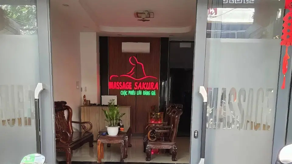 나트랑 사쿠라 마사지 사쿠라 마사지 입구 전경, 붉은 네온 조명과 전통 목재 의자가 배치된 웰컴 공간
