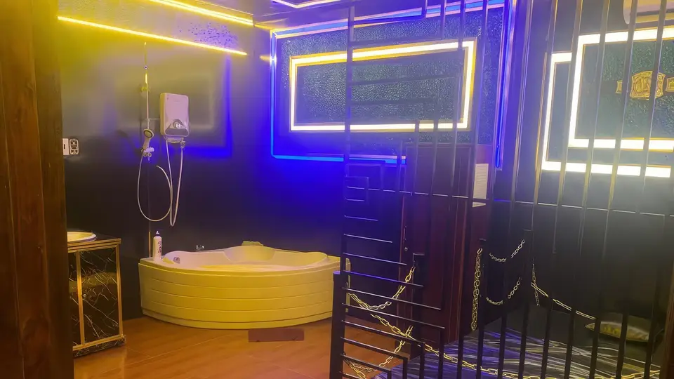 푸꾸옥 황궁 마사지 푸른색 네온 조명 아래 코너형 대형 자쿠지 욕조와 독특한 철제 인테리어가 돋보이는 황궁 마사지 룸