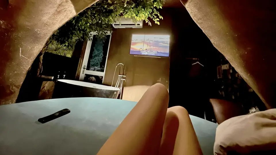 붕따우 떠이도 마사지 아치 구조 안에서 바라본 독립형 욕조와 벽걸이 TV, 그린 식물 장식이 어우러진 프리미엄 스위트 룸